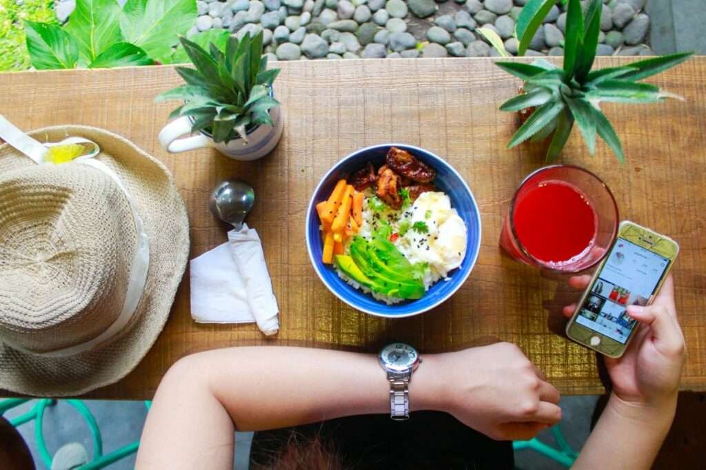 woman holding iphone while eating